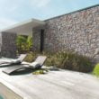 Terrasse extérieure en bois équipée de mobilier devant façade de maison moderne habillé en parement Tahoe ton rocaille