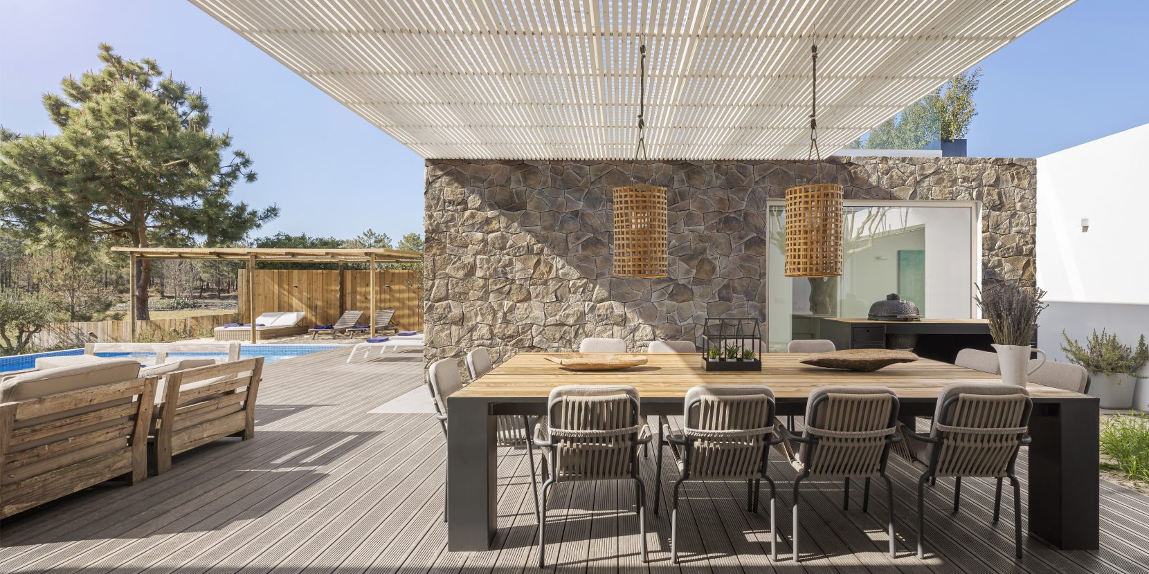 terrasse moderne avec piscine, grande table pour accueillir les invités, sol en bois, parement sur le mur Incerto ORSOL